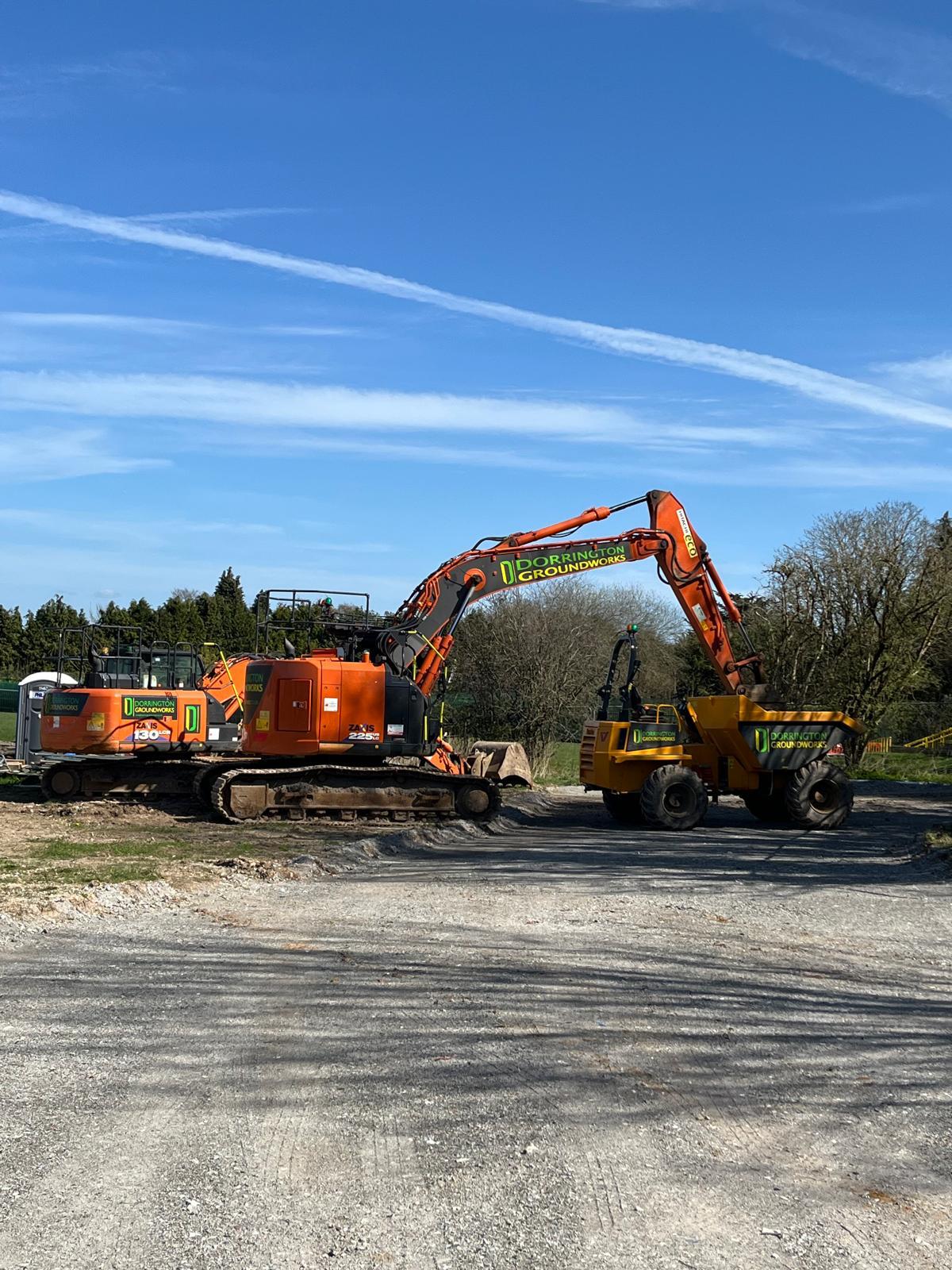 Orange excavator and dump truck on residential construction site